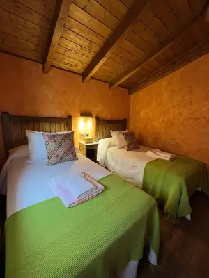 a bedroom with two beds with green sheets at La CasuKa VUT Fabero in Fabero