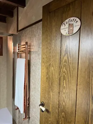 a bathroom with a wooden door and a white towel at La CasuKa VUT Fabero in Fabero