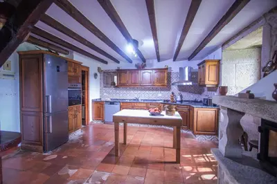 a kitchen with wooden cabinets and a table in it at Pazo del siglo XVII en el corazón de Galicia in Lalín