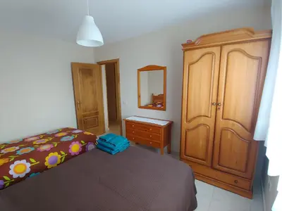 a bedroom with a bed and a wooden cabinet at Casa Aroa in Barreiros