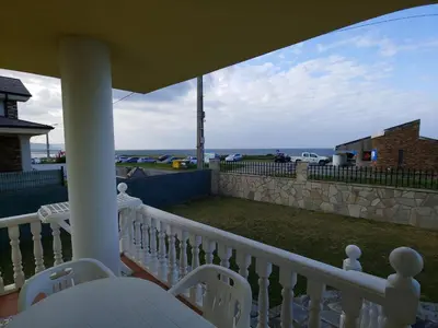 a porch with white chairs and a view of the ocean at Casa Aroa in Barreiros
