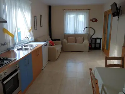 a kitchen with a sink and a living room at Casa Aroa in Barreiros