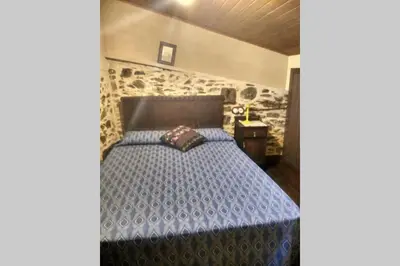 a bedroom with a bed with a blue comforter at Casa da Penisquela in O Barco de Valdeorras