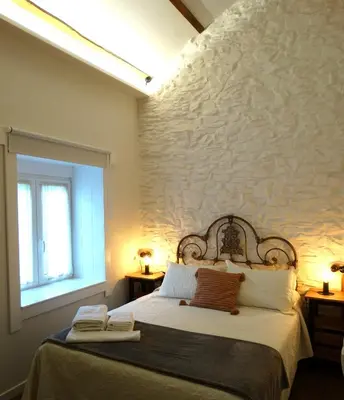 a bedroom with a bed and a stone wall at Apartamentos Minas de Silvarosa in Viveiro