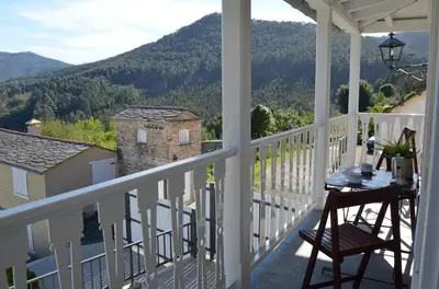 a balcony with a table and a view of the mountains at Apartamentos Minas de Silvarosa in Viveiro