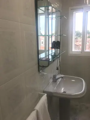 a white bathroom with a sink and a window at A boa vista in Melide