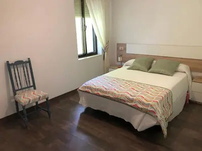a bedroom with a large bed and a chair at El Mirador de la Villa in Puebla de Sanabria