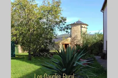 a stone building with a clock tower in a yard at AT El Manzano - Jardín & BBQ - Los Gayoles Rural in Castropol