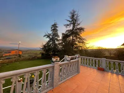 a white fence on a balcony with a sunset in the background at Casa con finca en Pol, Monforte de Lemos in Monforte de Lemos