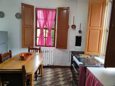 a kitchen with a table and a window with pink curtains at Casa con finca en Pol, Monforte de Lemos in Monforte de Lemos