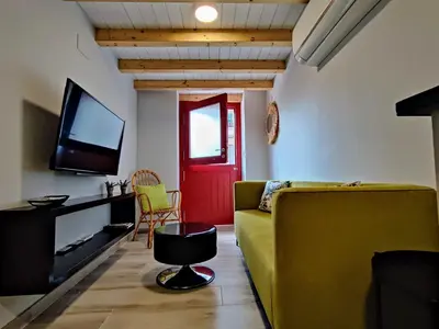 a living room with a yellow couch and a red door at La Casita de la Ribeira Sacra in Monforte de Lemos