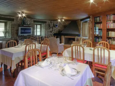 a dining room with white tables and chairs and a fireplace at Casa Baralló in Lobios
