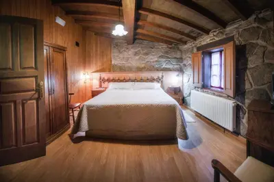 a bedroom with a bed and a stone wall at Casa Baralló in Lobios