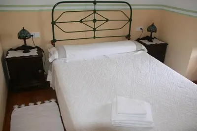 a bedroom with a large bed with white sheets at Casa Pousadoira in Miño
