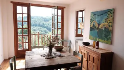 a dining room with a wooden table and a large window at El Escondite Inglés in Pantón