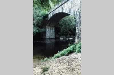 an old stone bridge over a river at El Escondite Inglés in Pantón