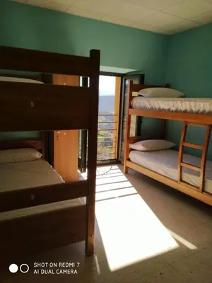 a room with three bunk beds with a balcony at Albergue La Plaza in Tineo