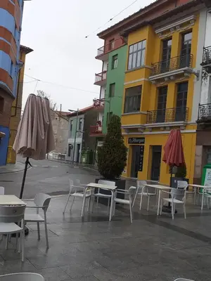 a group of tables and chairs and an umbrella on a street at Albergue La Plaza in Tineo