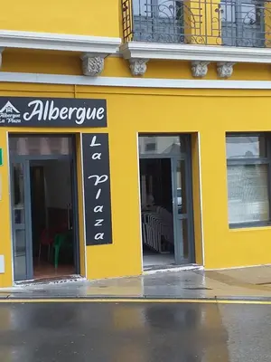 a yellow building with a sign for a restaurant at Albergue La Plaza in Tineo