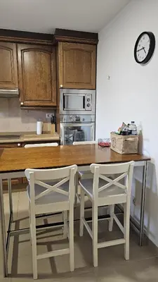 a kitchen with a wooden table and two white chairs at Casa de piedra, A Lameira in A Coruña