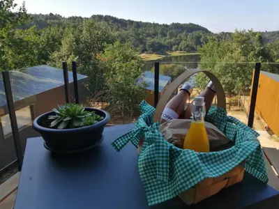 a picnic table with a bottle of orange juice and a basket at Cabanas Mirador Cachamuíña in Ourense