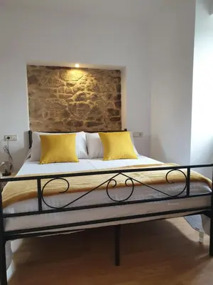 a bed with yellow pillows and a brick wall at Villa Rosa in Silleda