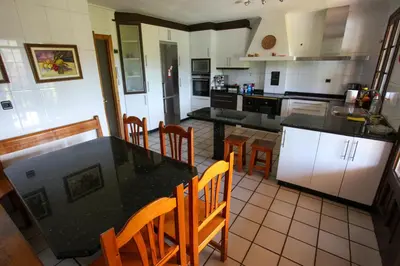 a kitchen with a black counter top and wooden chairs at Espectacular Casa con Piscina en Allariz in Allariz