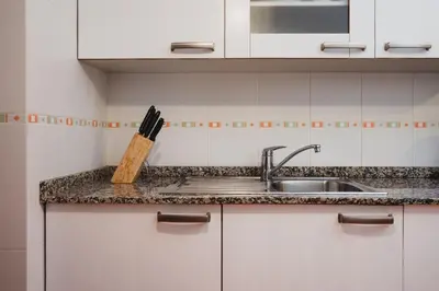 a kitchen counter with a sink and a knife block at Apartamentos LÓRIEN Milladoiro in Milladoiro