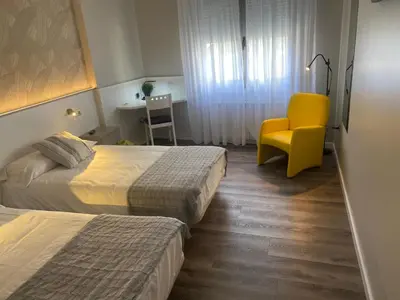 a hotel room with two beds and a yellow chair at Villa Alta in Villalba