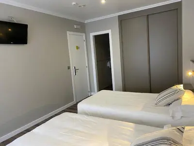 a bedroom with two beds and a tv on the wall at Villa Alta in Villalba