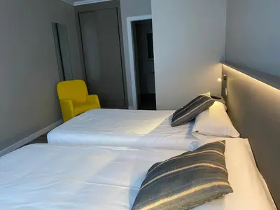 a bedroom with two beds and a yellow chair at Villa Alta in Villalba