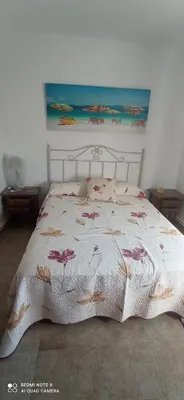 a bed with a white bedspread with pink flowers on it at Casa Campanita in Ribadeo
