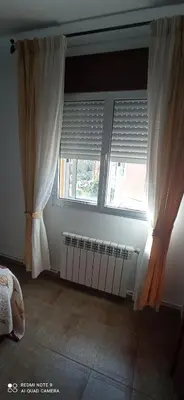 a bedroom with white curtains and a window at Casa Campanita in Ribadeo