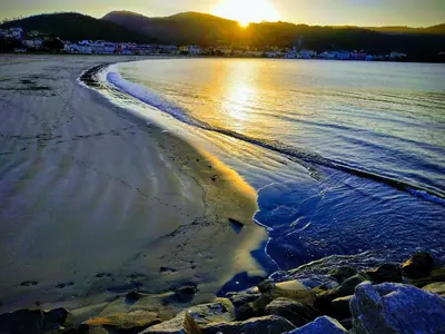 a beach with the sun setting over the water at Indiano 2K in Viveiro