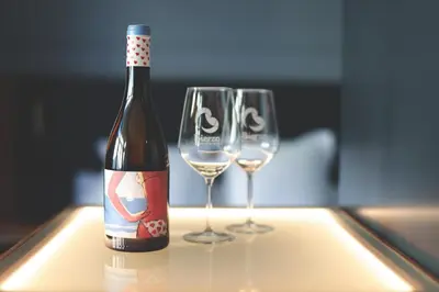a bottle of wine and two wine glasses on a table at Azotea Suites in Ponferrada