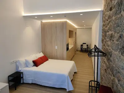 a bedroom with a white bed and a kitchen at Apartamentos A pousa do Asma in Chantada