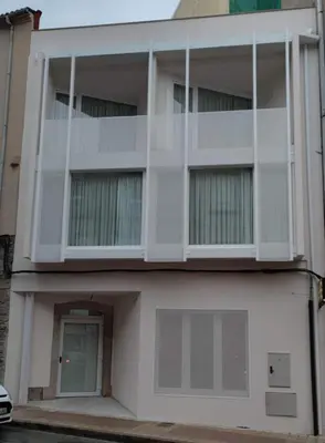 a white building with a green door and a building at Apartamentos A pousa do Asma in Chantada