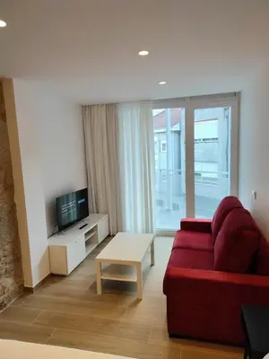 a living room with a red couch and a tv at Apartamentos A pousa do Asma in Chantada