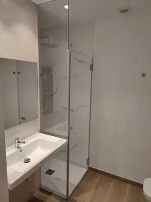 a bathroom with a glass shower and a sink at Apartamentos A pousa do Asma in Chantada