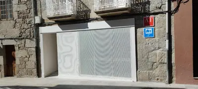 a white garage door on the side of a building at Apartamentos A pousa do Asma in Chantada