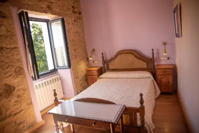 a bedroom with a bed with a table and a window at Casa Fonte do Barro SPA opcional, de pago in Santiago de Compostela