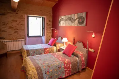 a red room with two beds and a window at Casa Fonte do Barro SPA opcional, de pago in Santiago de Compostela