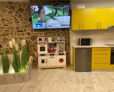 a kitchen with yellow cabinets and a toy stove at As Penedas, Casa dos Arcos in Sober