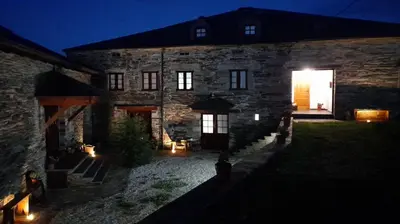 a large stone building with a courtyard at night at La Posada de Oscos II in Santa Eulalia de Oscos