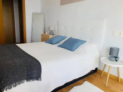 a bedroom with a large white bed with blue pillows at Apartamentos LAMAROSA - DELUX -PARKING- in Burela de Cabo