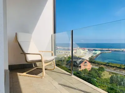 a white chair sitting on a balcony looking out at the ocean at Apartamentos LAMAROSA - DELUX -PARKING- in Burela de Cabo