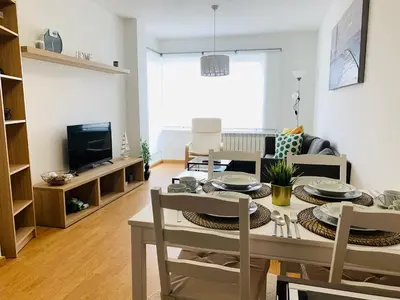a kitchen and living room with a table and chairs at Apartamentos LAMAROSA -PLAYA URBANA in Burela de Cabo