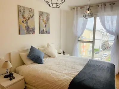 a bedroom with a large bed and a window at Apartamentos LAMAROSA -PLAYA URBANA in Burela de Cabo