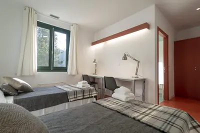 a bedroom with two beds and a desk and a window at Peares Center Chalet in Carballedo
