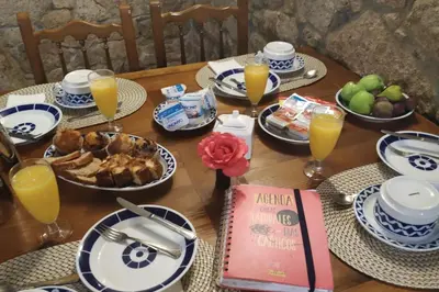 a wooden table with plates of food and orange juice at Duerming Casa Vilamor in Vilamor